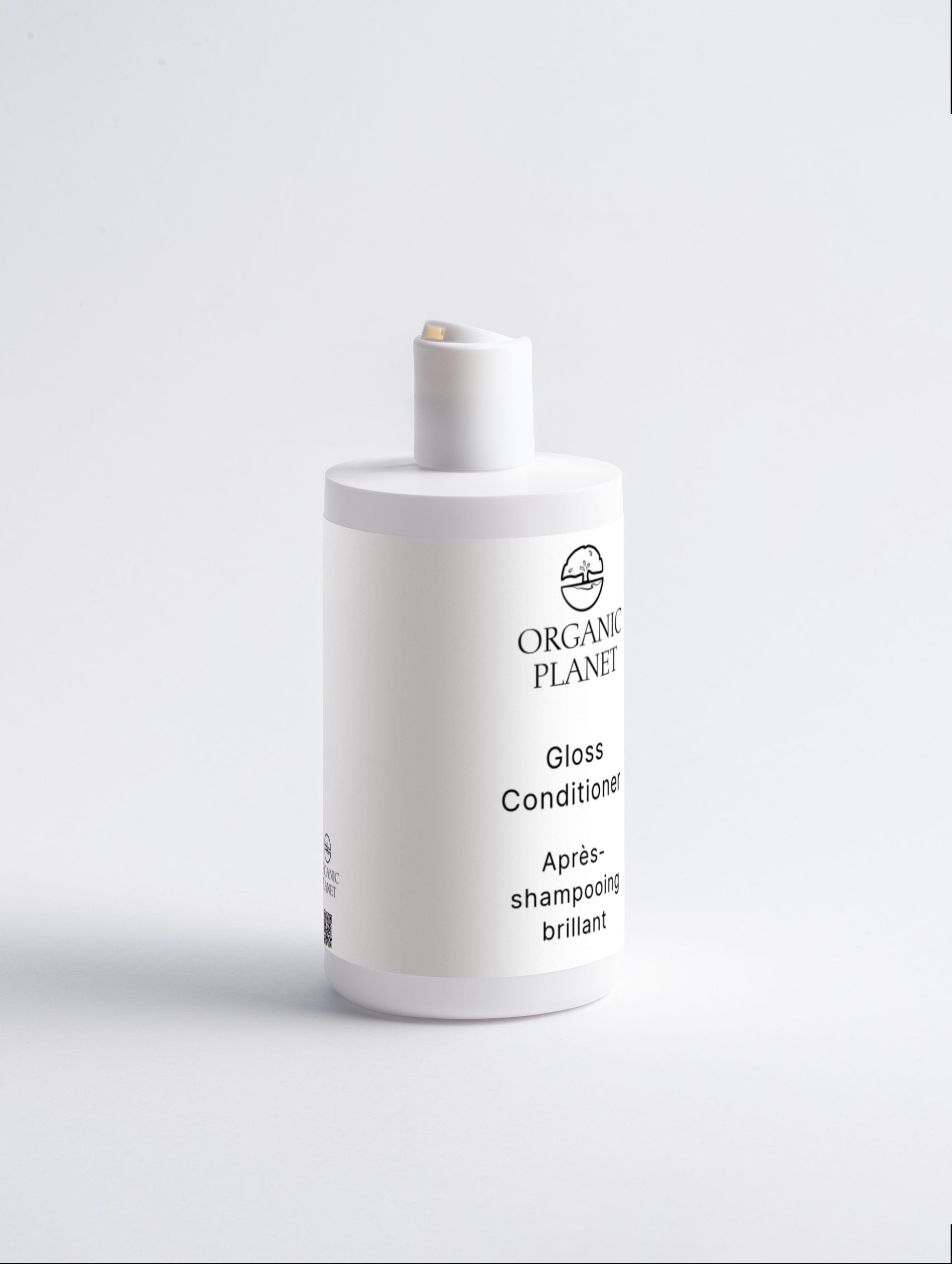 White bottle of Organic Planet Gloss Conditioner on a light gray background. This conditioner nourishes hair ends to prevent breakage and split ends, leaving hair smoother and silkier. Suitable for all skin types, it helps improve manageability and adds a healthy shine, making styling easier.